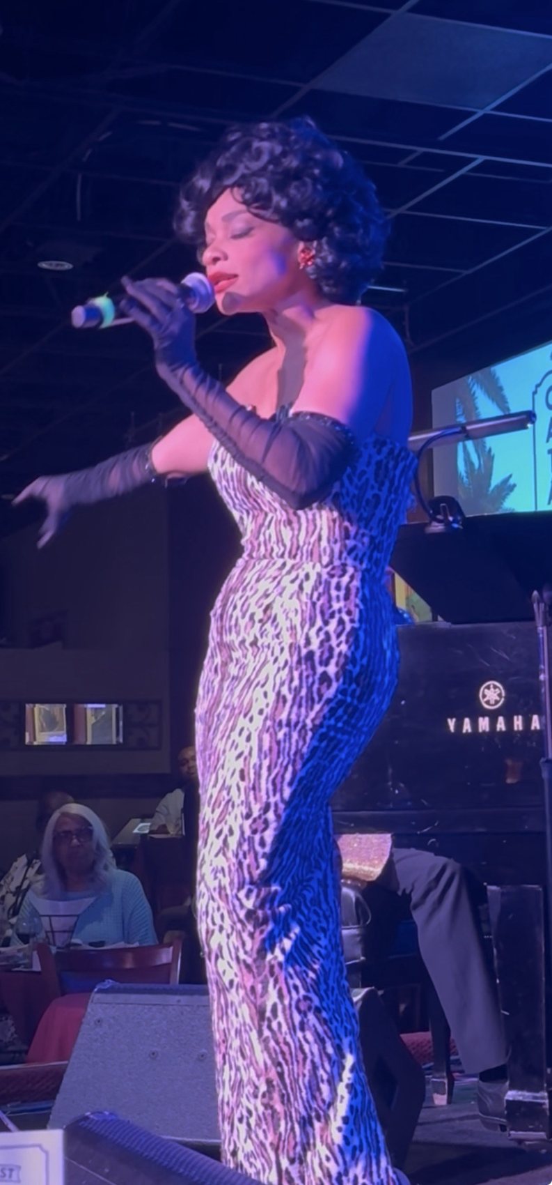 Thomasina Gross performing as Eartha Kitt in a leopard-print gown and black opera gloves